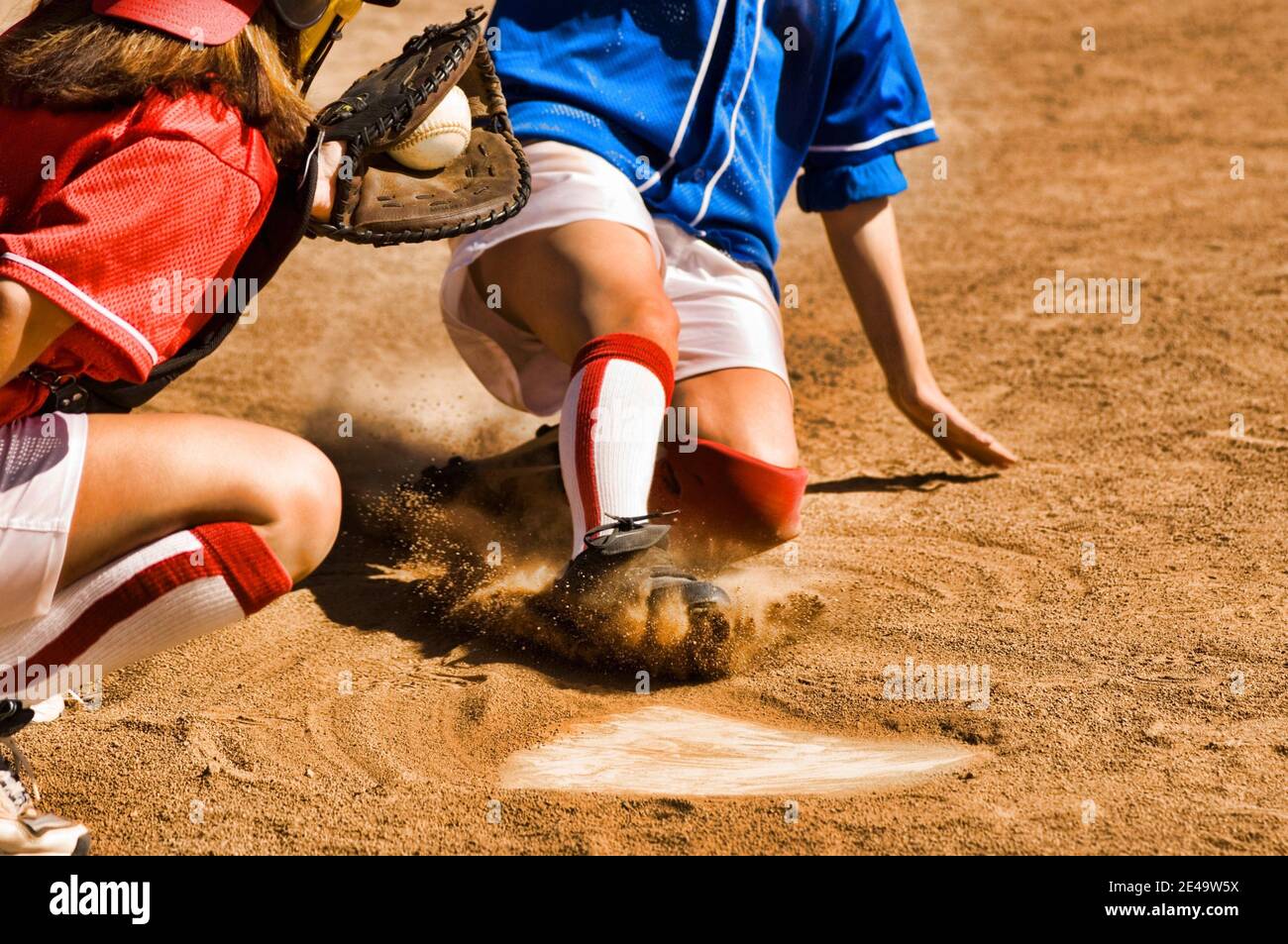 Cropped photo of softball player sliding into home plate Stock Photo