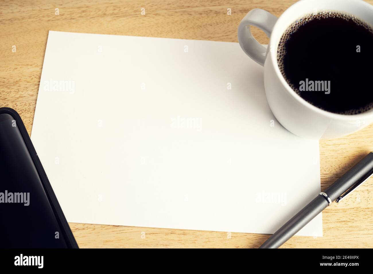 Blank paper on wooden desk table with cup of coffee, pen and smartphone.  Mock up template. Study or business concept Stock Photo - Alamy