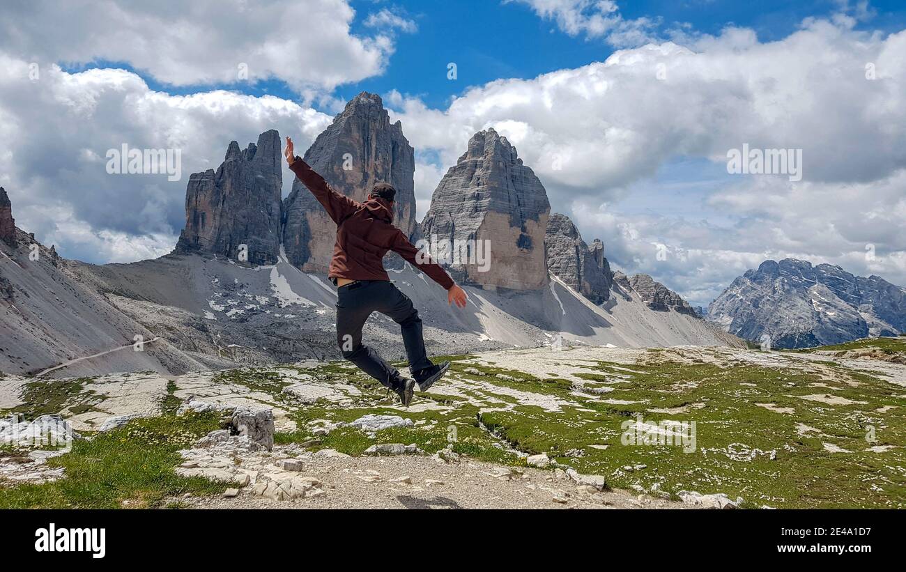 Hiker jumping up at the top of a mountain with a breathtaking view ...