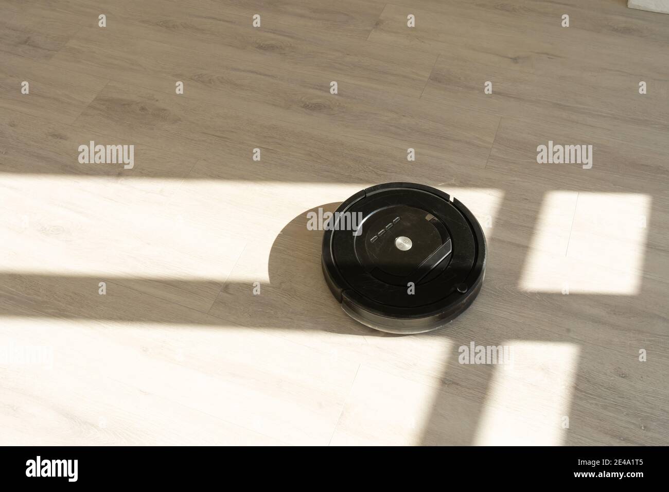 Robotic vacuum cleaner on laminate wood floor in living room Stock Photo