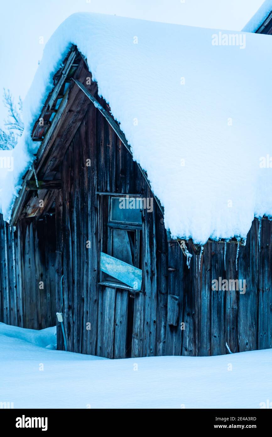 snowy hut with icicles on the roof. Verschneiter Stadel mit Eiszapfen an der Dachrinne. Winterszene. winter snow cabin icicles wooden facade weathered Stock Photo