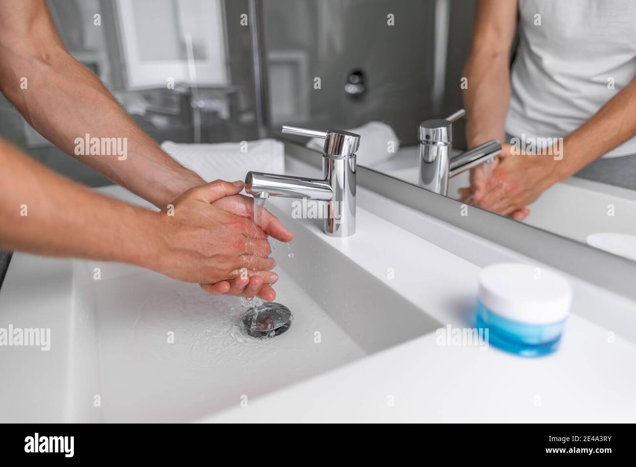 Man washing hands in hot water bathroom faucet sink running water for clean wash Stock Photo