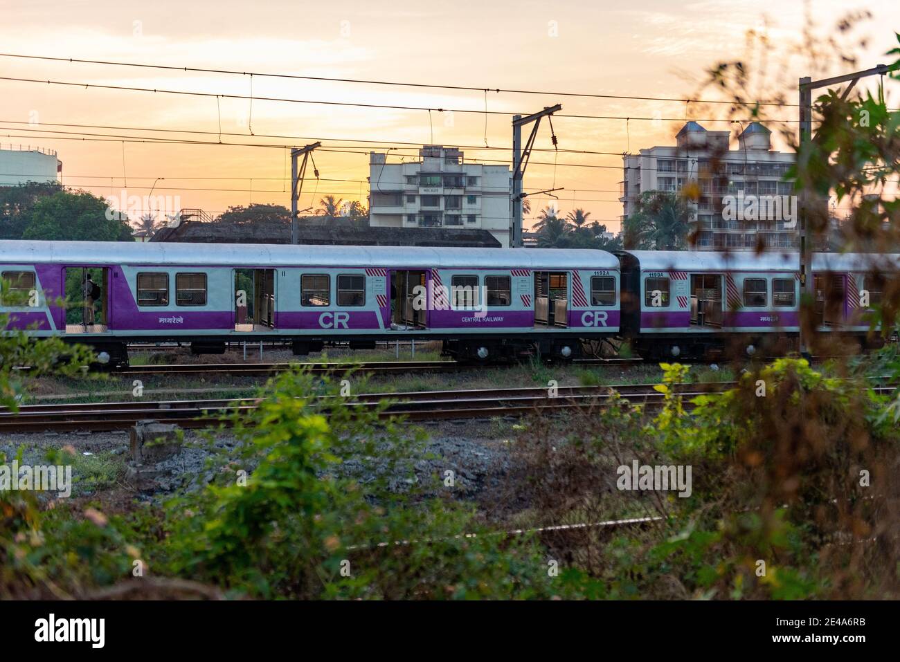 Empty MRVC Siemens EMU rake on Harbour line against orange sunset sky and high buildings at Panvel Railway Station outer Stock Photo