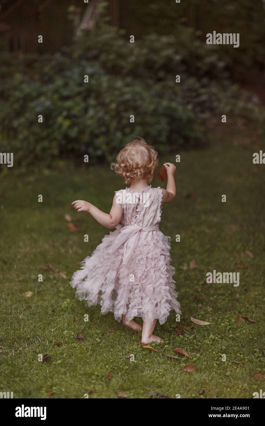 Little girl in a fancy pink dress playing outdoors Stock Photo - Alamy