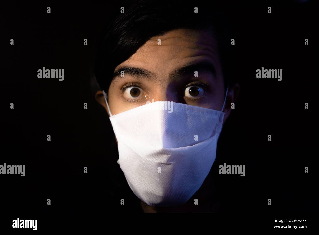 Portrait of a man with a disposable white face mask looking aside at ...