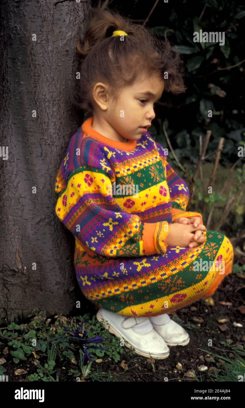 unhappy little girl sitting under tree Stock Photo