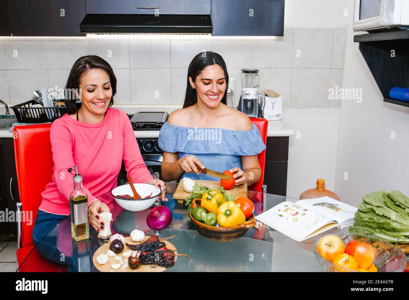 latin women cooking vegetables food and having fun in a mexican kitchen in Mexico city Stock Photo