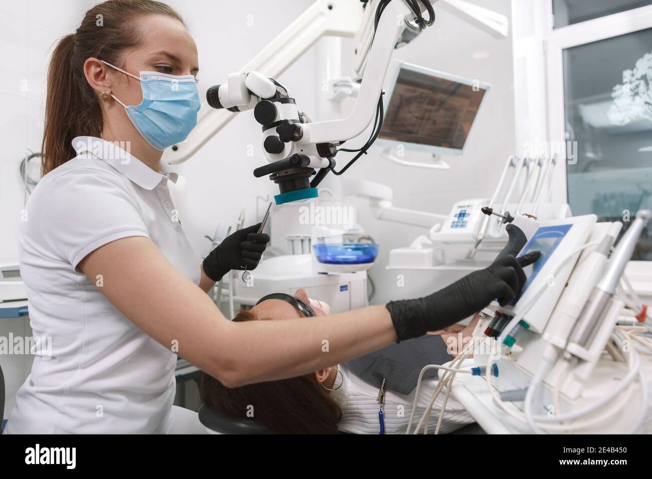 Low angle shot of a professional dentist wearing medical face mask and gloves, using modern