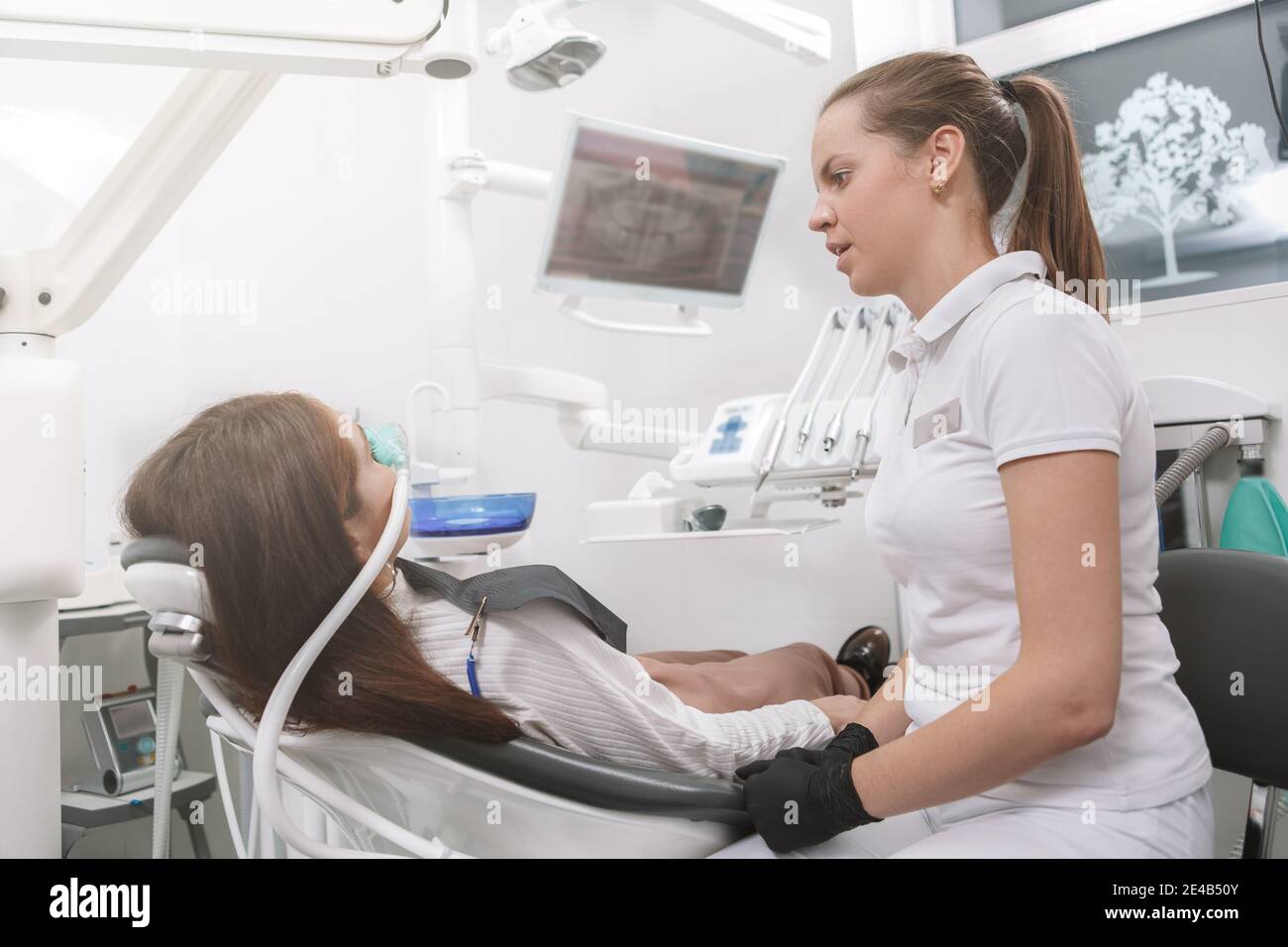 Dentist talking to her patient after putting inhalation sedation face mask on her Stock Photo