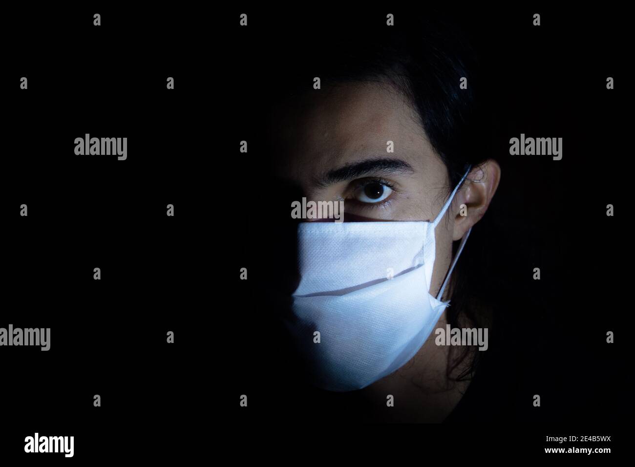 Portrait of a man with a disposable white face mask looking aside at ...