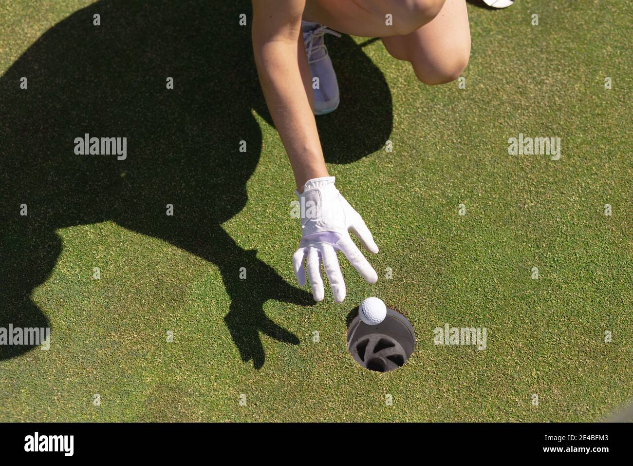 Low section of caucasian woman playing golf dropping ball in the hole Stock Photo