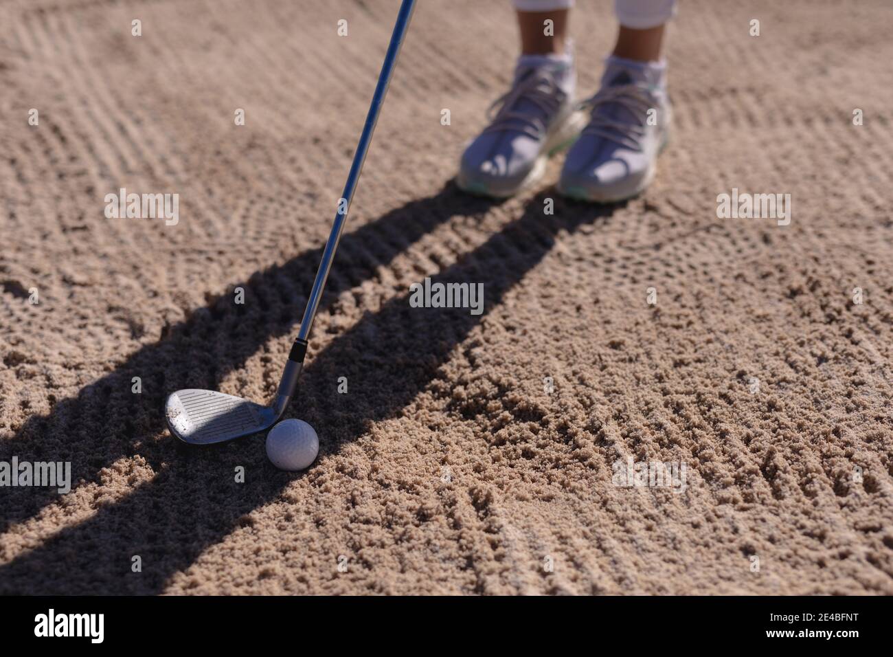 Low section of caucasian woman playing golf positioning club before taking shot from bunker Stock Photo