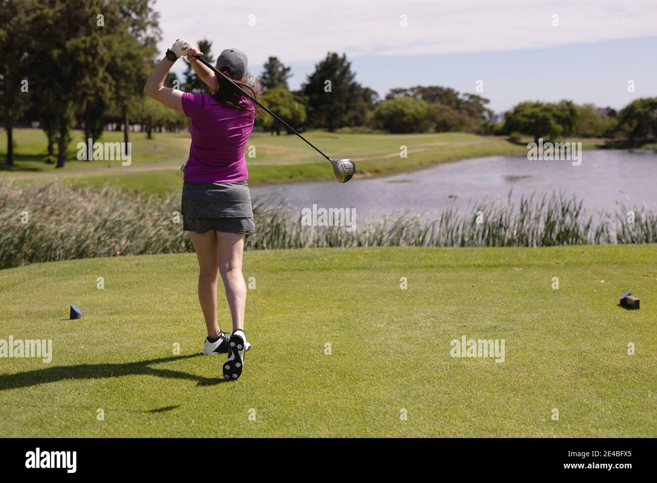 Caucasian woman playing golf swinging club and taking a shot Stock Photo