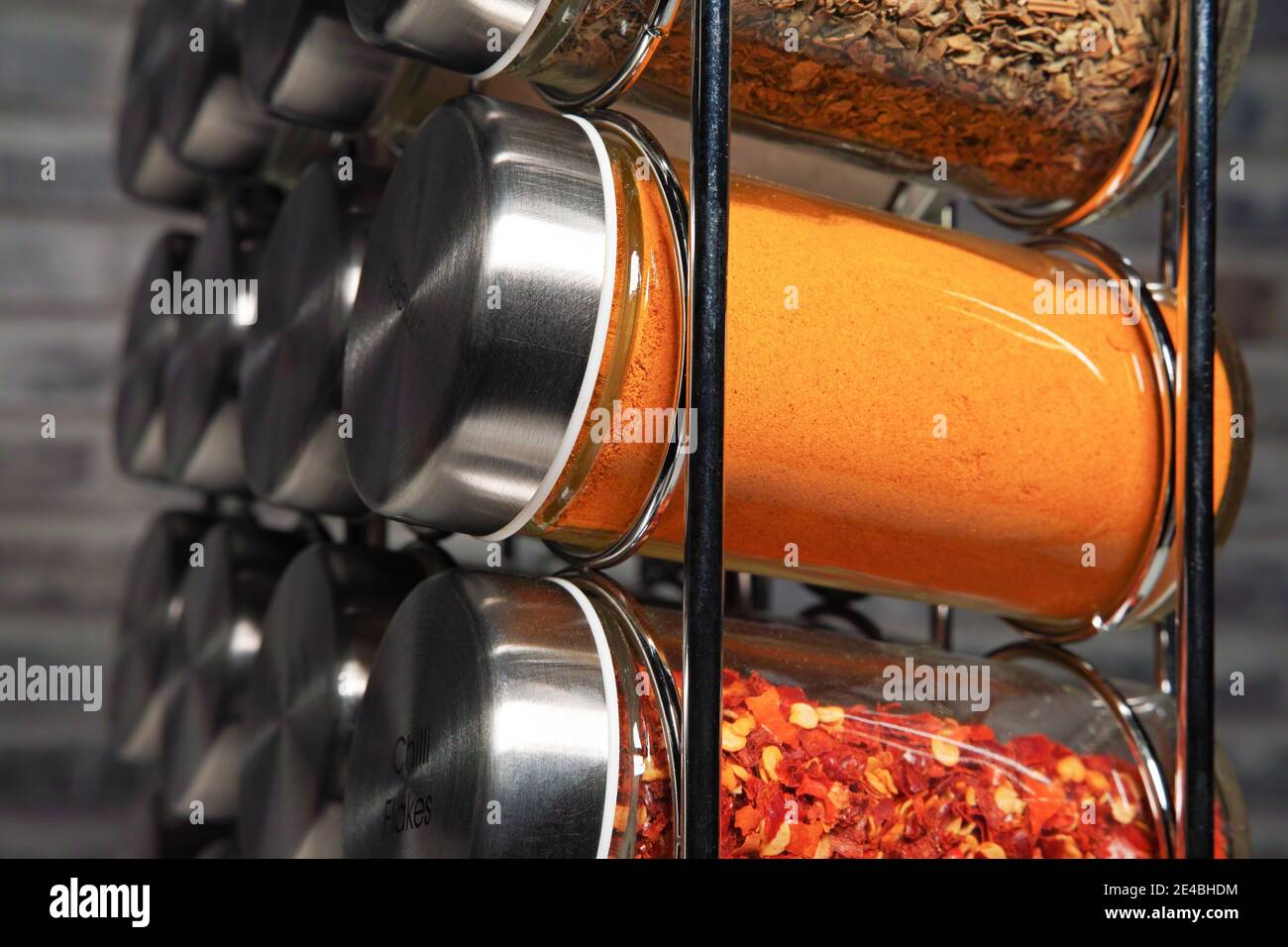 A metal spice rack with many glass bottles filled with different spices, studio shot Stock Photo