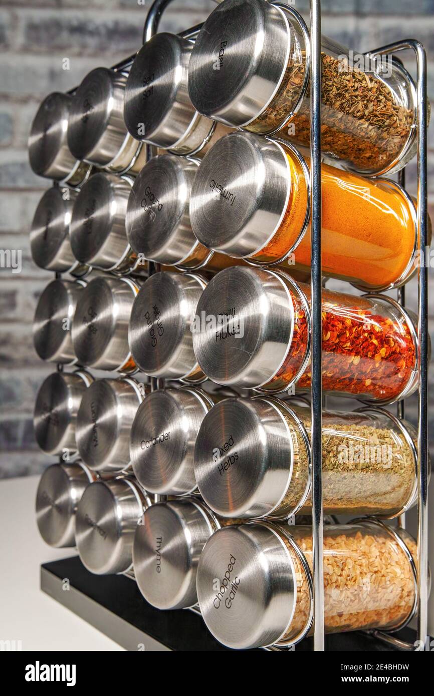 A metal spice rack with many glass bottles filled with different spices, studio shot Stock Photo