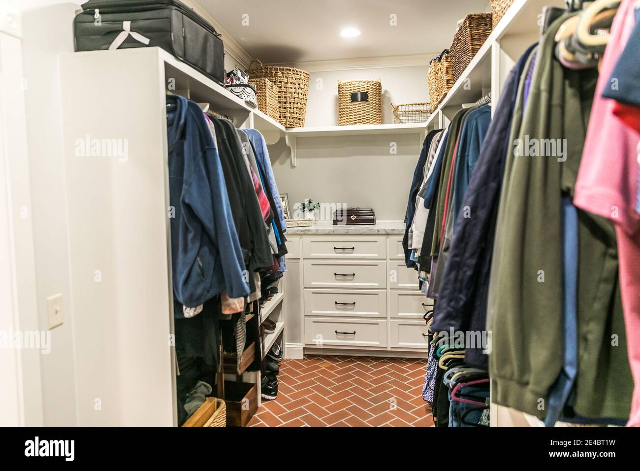 A clean and organized closet with some hanging clothes and shelves Stock Photo