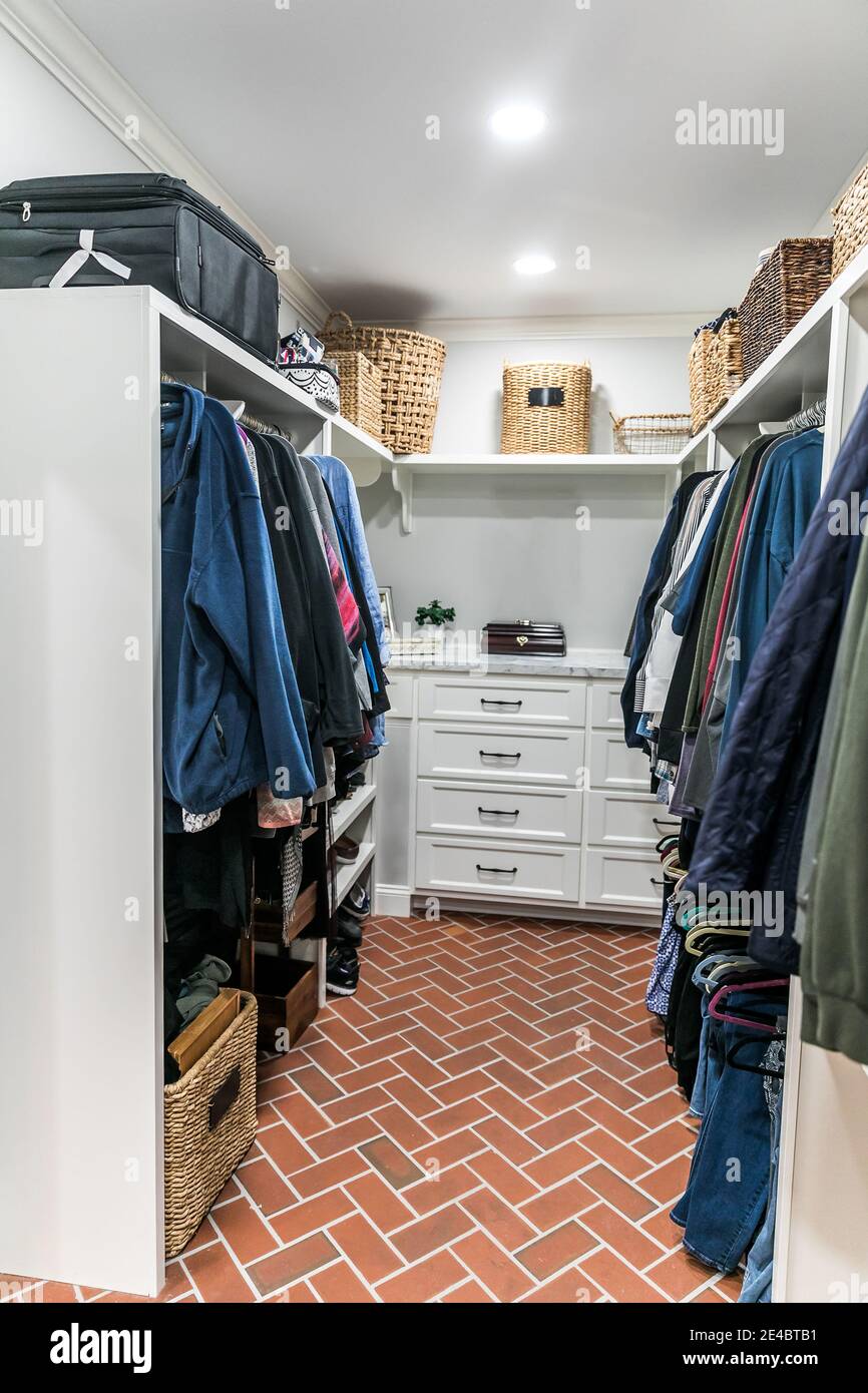 A clean and organized closet with some hanging clothes and shelves Stock Photo
