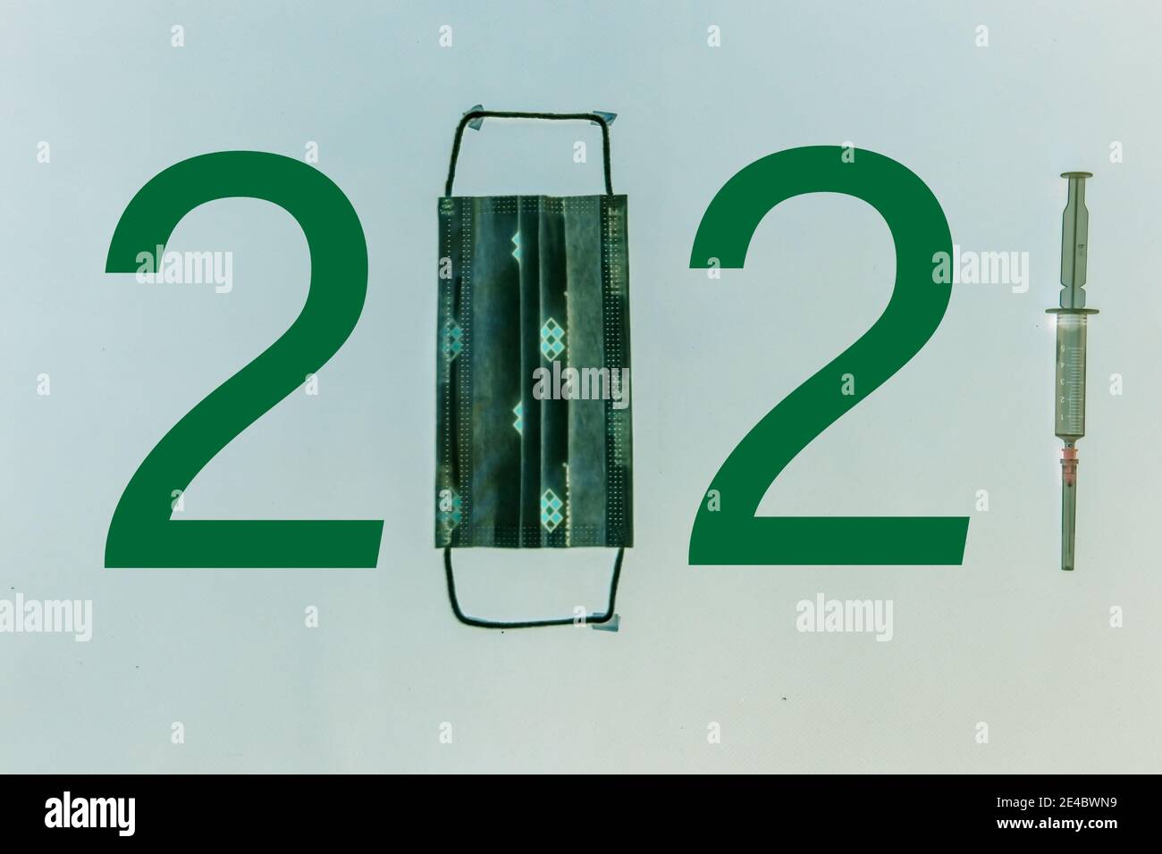 The number 2021 written with mask, number and syringe. A design considered due to Covid-19. Different symbols in the background. 2021 year themed. Stock Photo