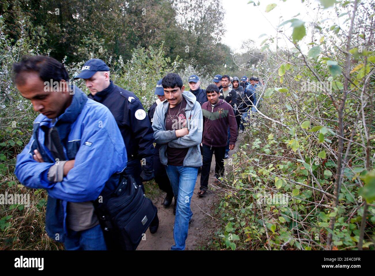 French gendarmes and police officers block a would-be-immigrant in a wooded area known as 'the jungle' in Calais, northern France, on September 22, 2009, as they dismantle the makeshift tent camp. The French government announced on September 16, 2009 that Stock Photo