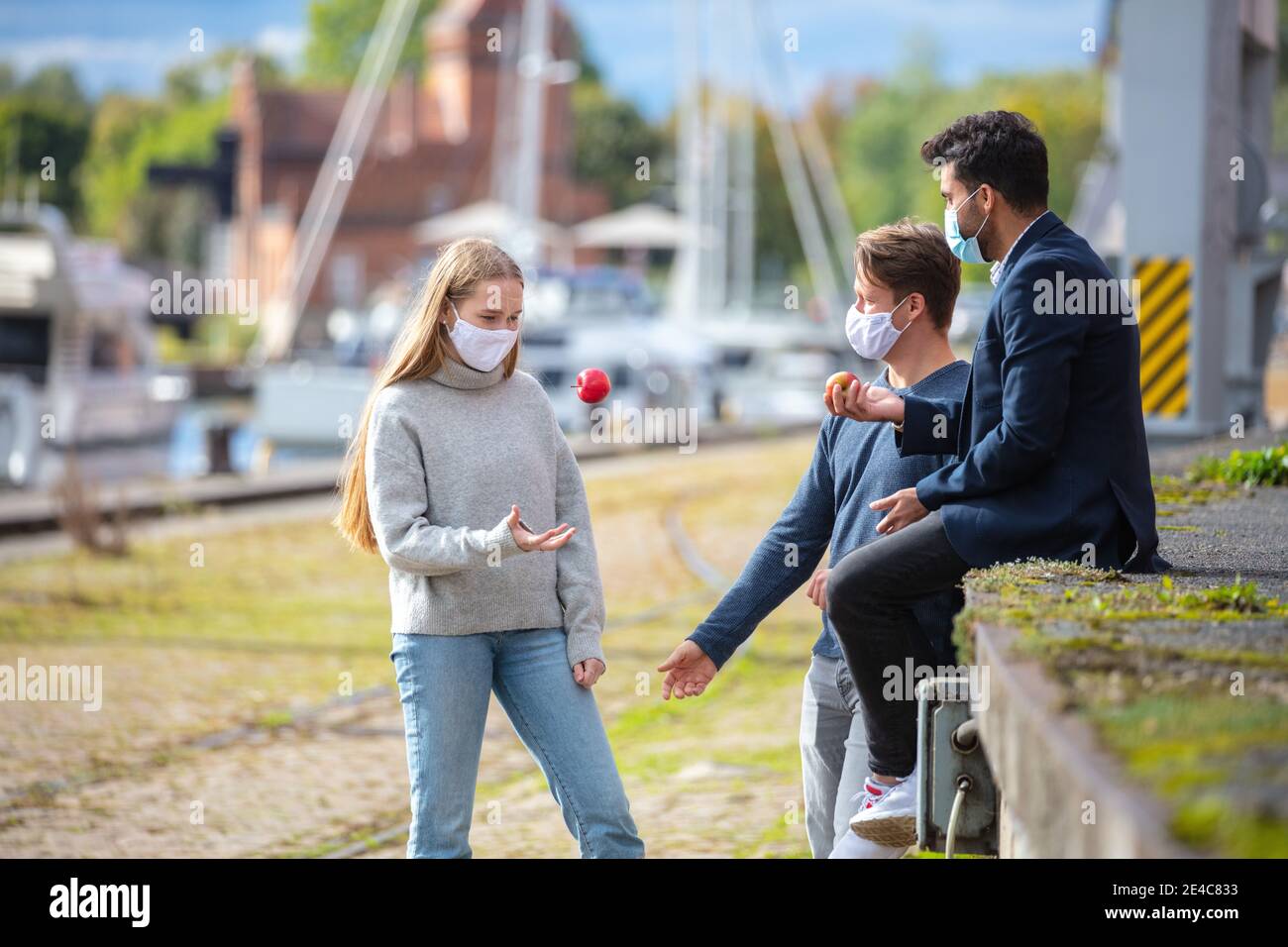 Two men and a woman in Corona time, with everyday masks, out and about in the city. Leisure time with mask outdoors. Stock Photo