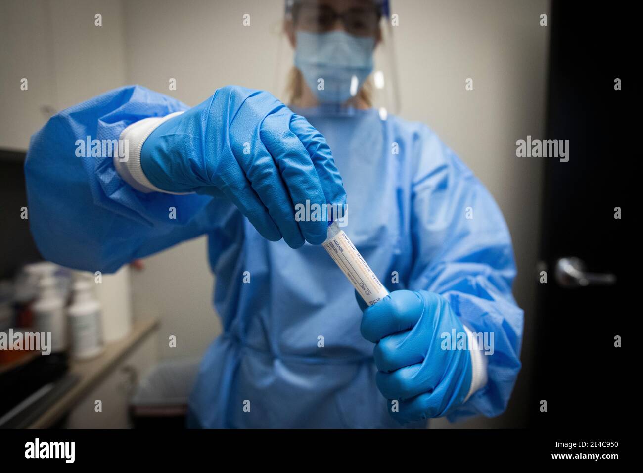 A pharmacist in PPE(personal protective equipment) holds a COVID-19 test in a tube at a pharmacy in Amherstview, Ontario on Friday, January 22, 2021, Stock Photo