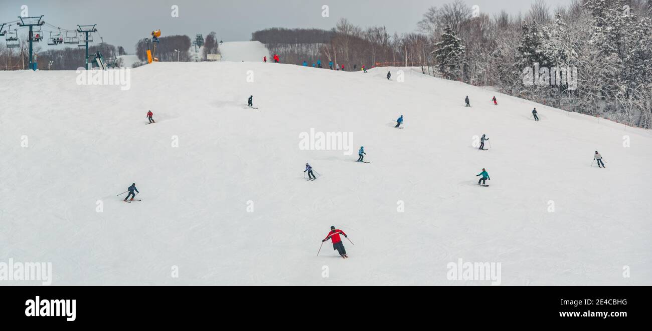 View of mountain ski slope with skiers and snowboarders going fast downhill. Alpine skiing and snowboarding. Panoramic view of winter sports nature Stock Photo