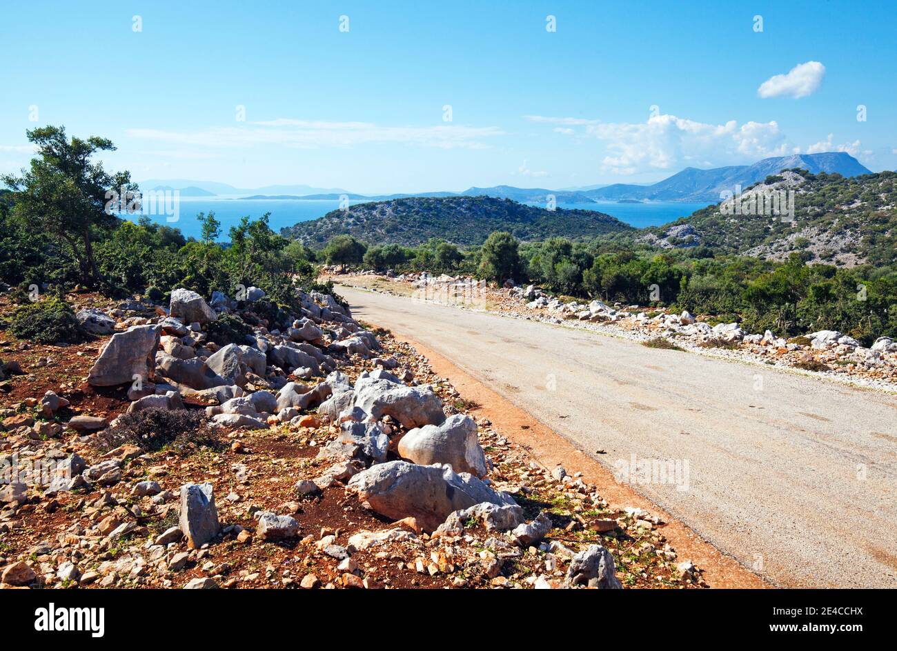 A narrow country road leads through the mountainous region in the hinterland of Astakos in central Greece, with a view of the island of Kalamos Stock Photo