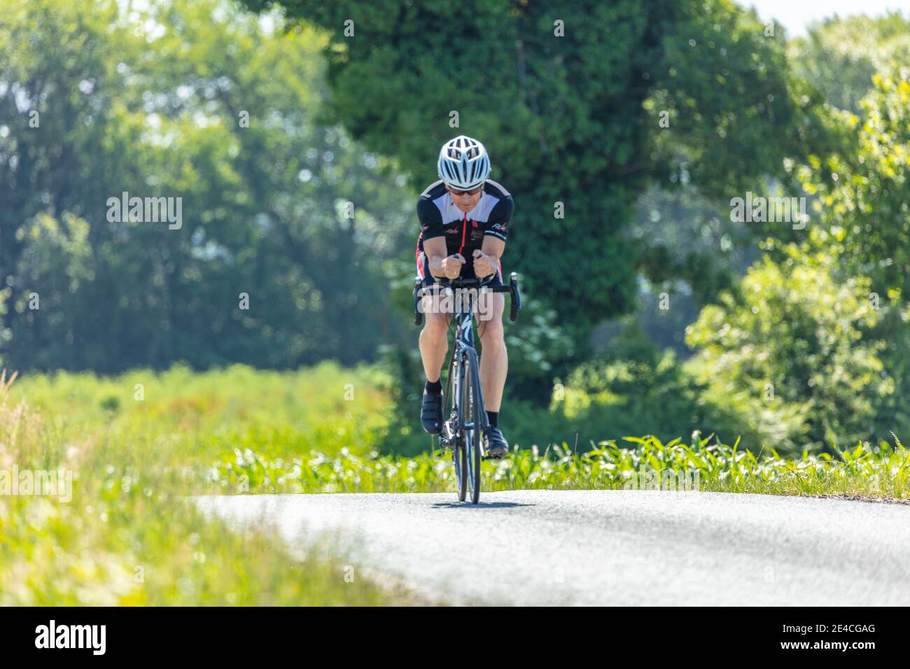Man 50 plus, rides his racing bike through the countryside in summer. raining for triathlon Stock Photo