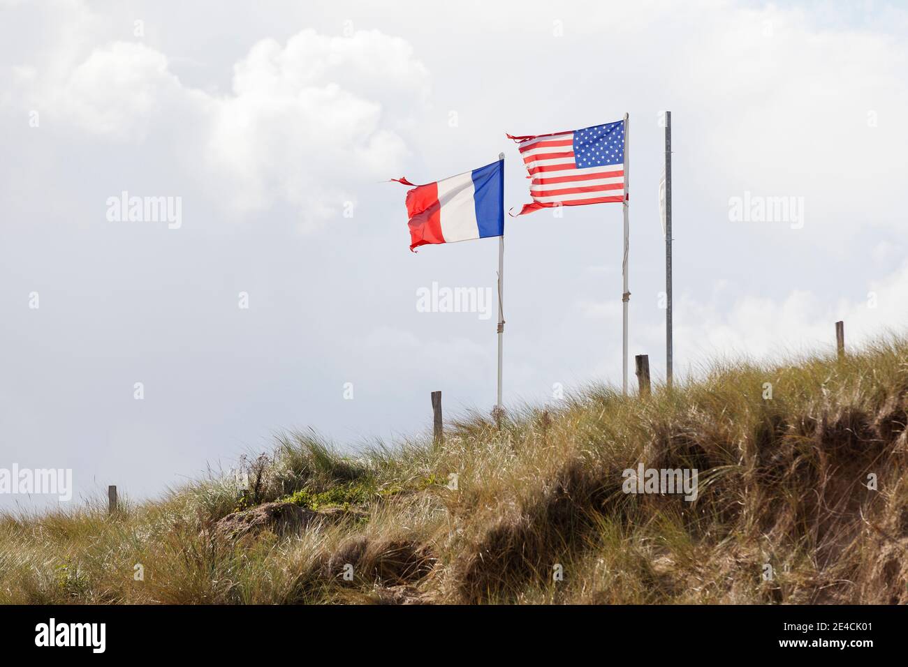 The French and American flags blow in the wind above the dunes of Utah Beach. Normandy, France Stock Photo