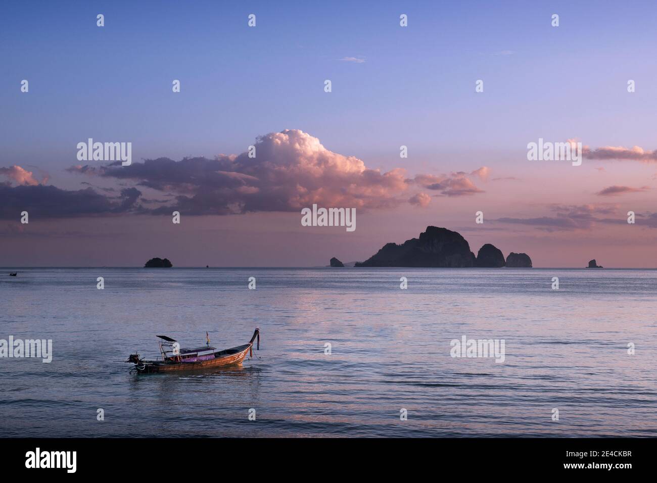A longtail boat anchors off the coast of Ao Nang, Krabi at sunset Stock Photo