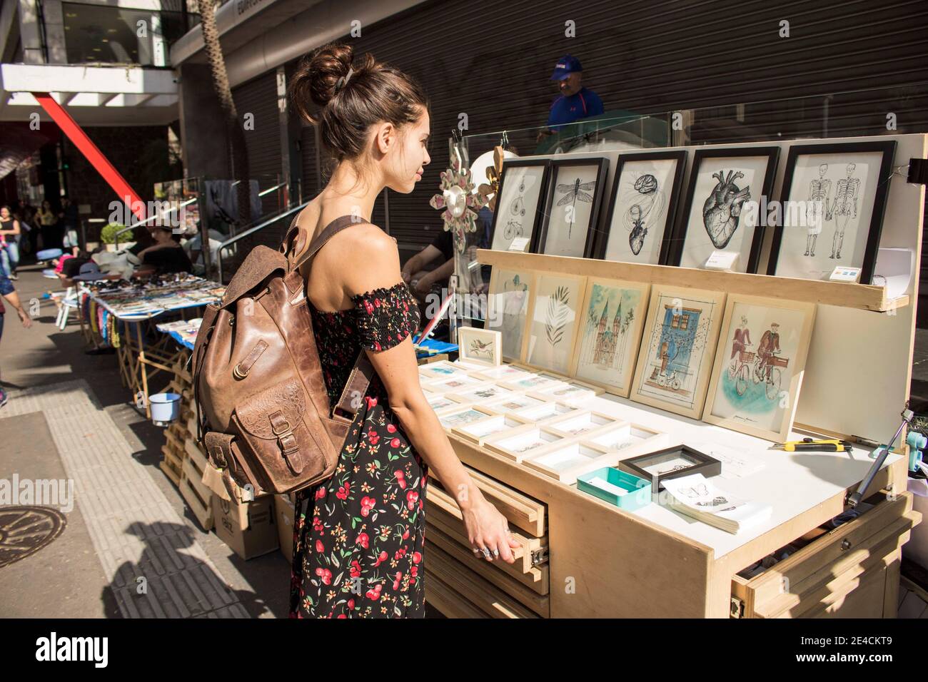 São Paulo / São Paulo / Brazil - 08 19 2018: Pretty young lovely model woman choosing a drawing or a painting to buy at a market place. Stock Photo