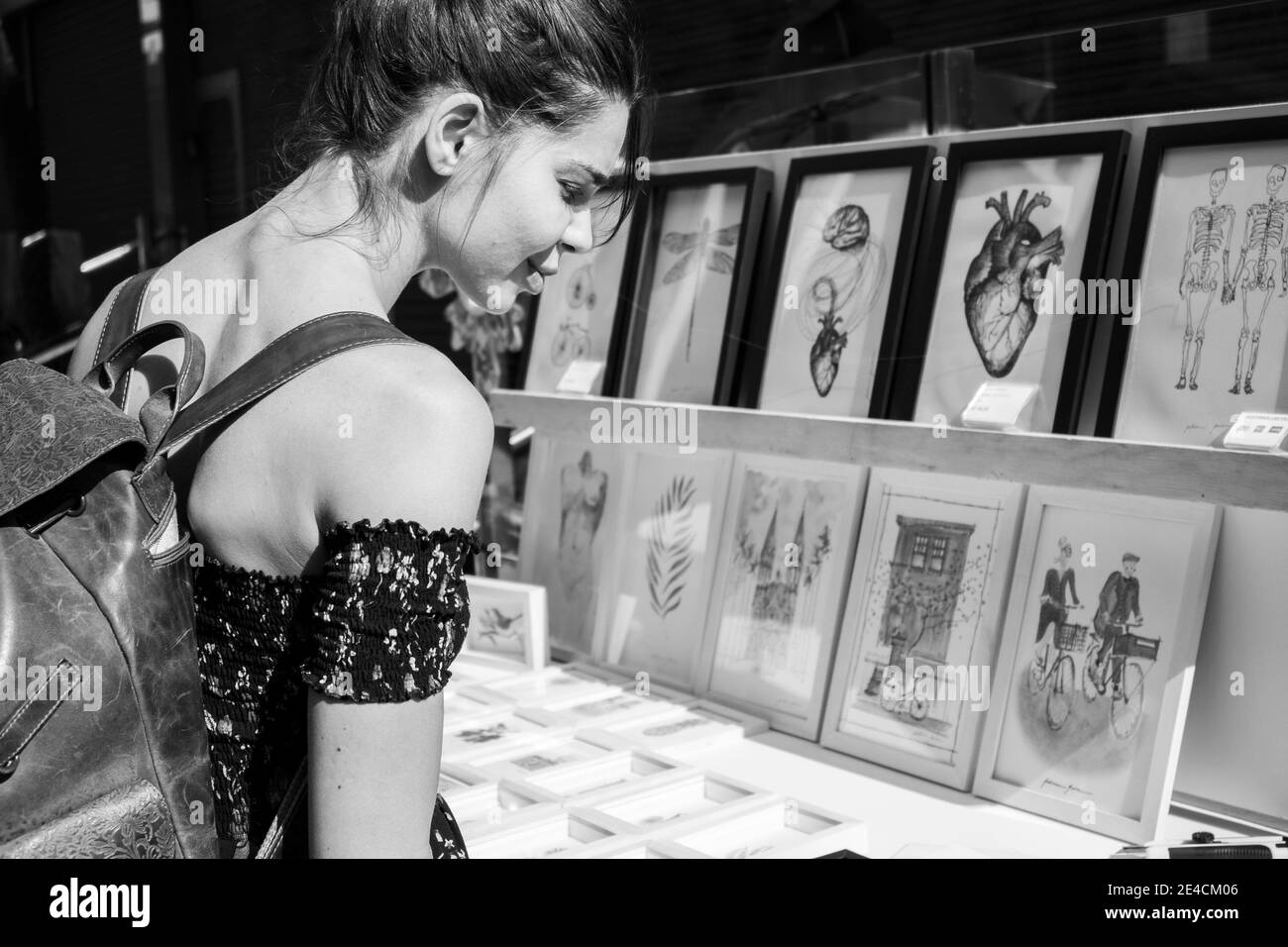São Paulo / São Paulo / Brazil - 08 19 2018: Pretty young model woman choosing a drawing or a painting to buy at a street [Black and White version] Stock Photo