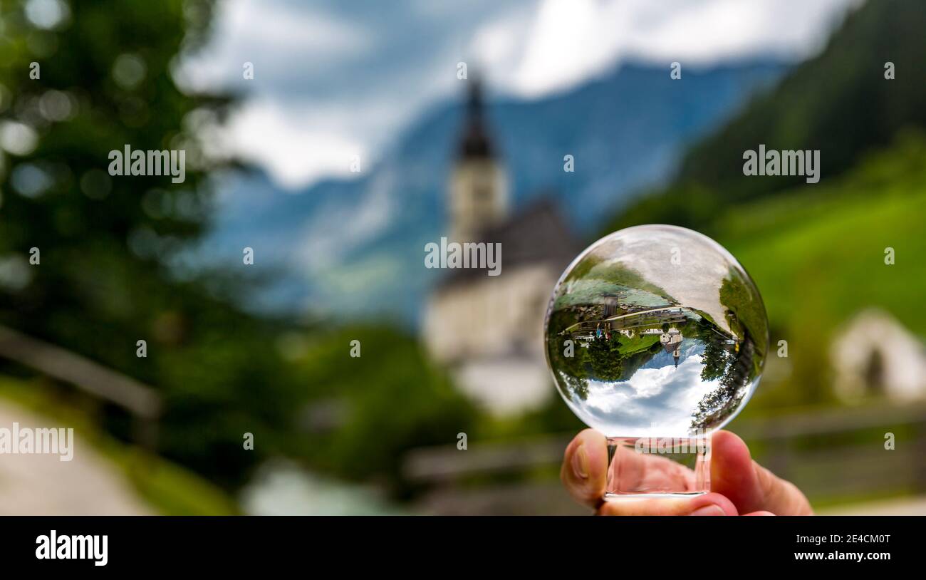 View through glass ball to the parish church of St. Sebastian, Ramsauer Ache, in the back Reiteralpe, Ramsau, Berchtesgaden, Berchtesgadener Land, Upper Bavaria, Bavaria, Germany, Europe Stock Photo