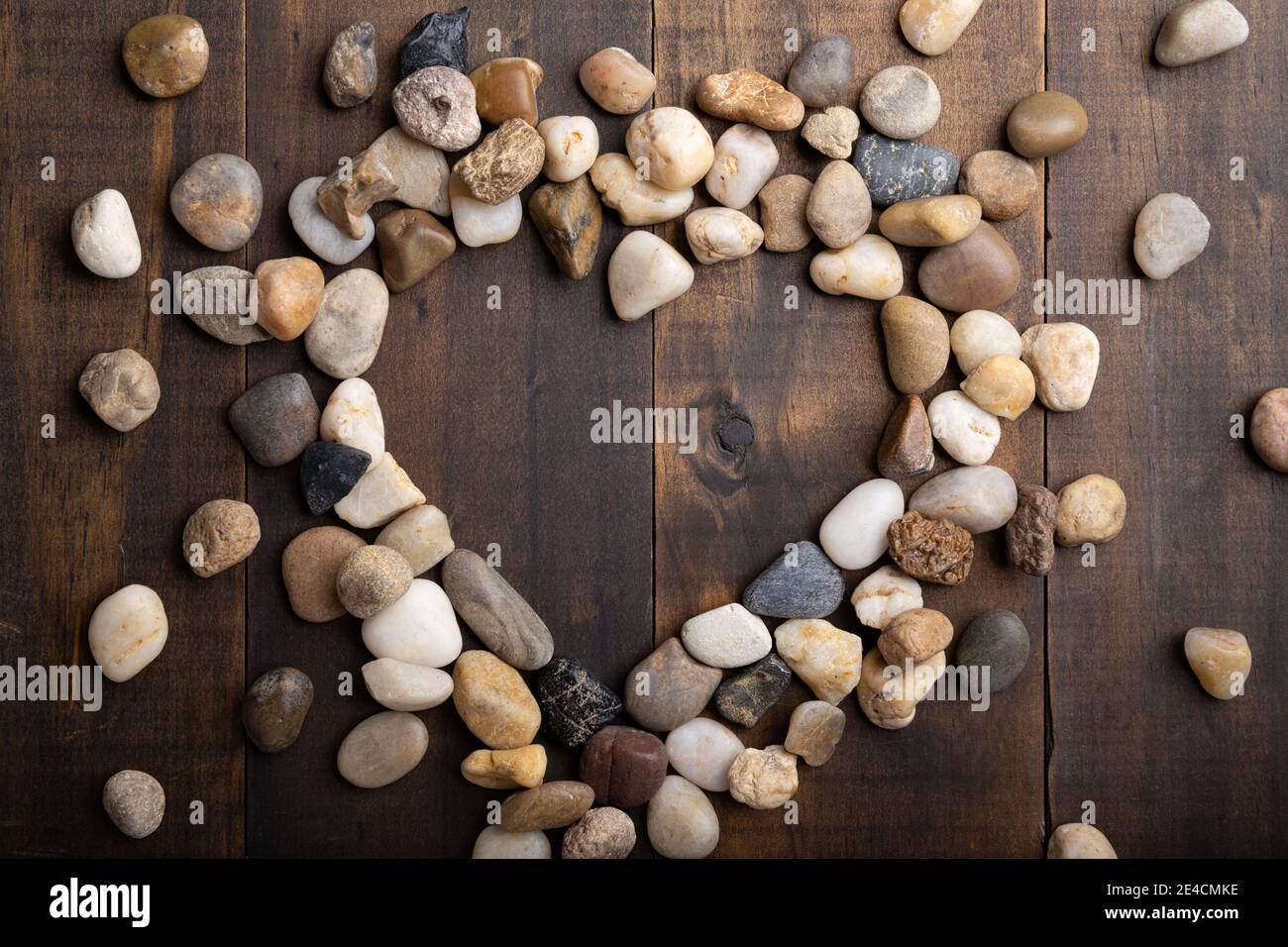 love concept image of heart shape frame made of round pebbles on wooden background Stock Photo