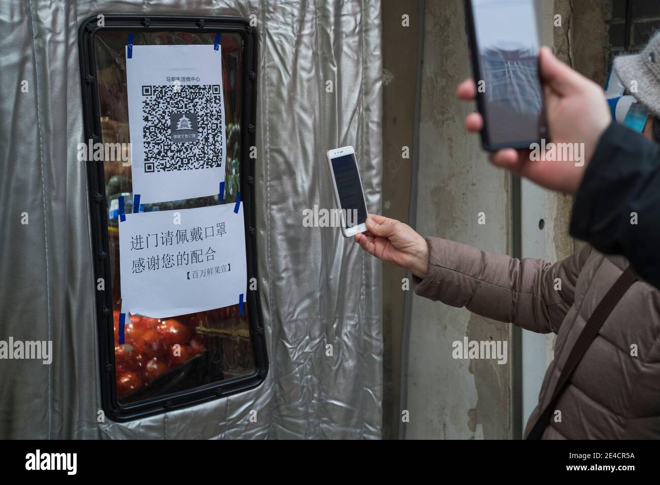 Residents scan a QR code to track their health status before entering a supermarket in Beijing, China January 23, 2021. Stock Photo