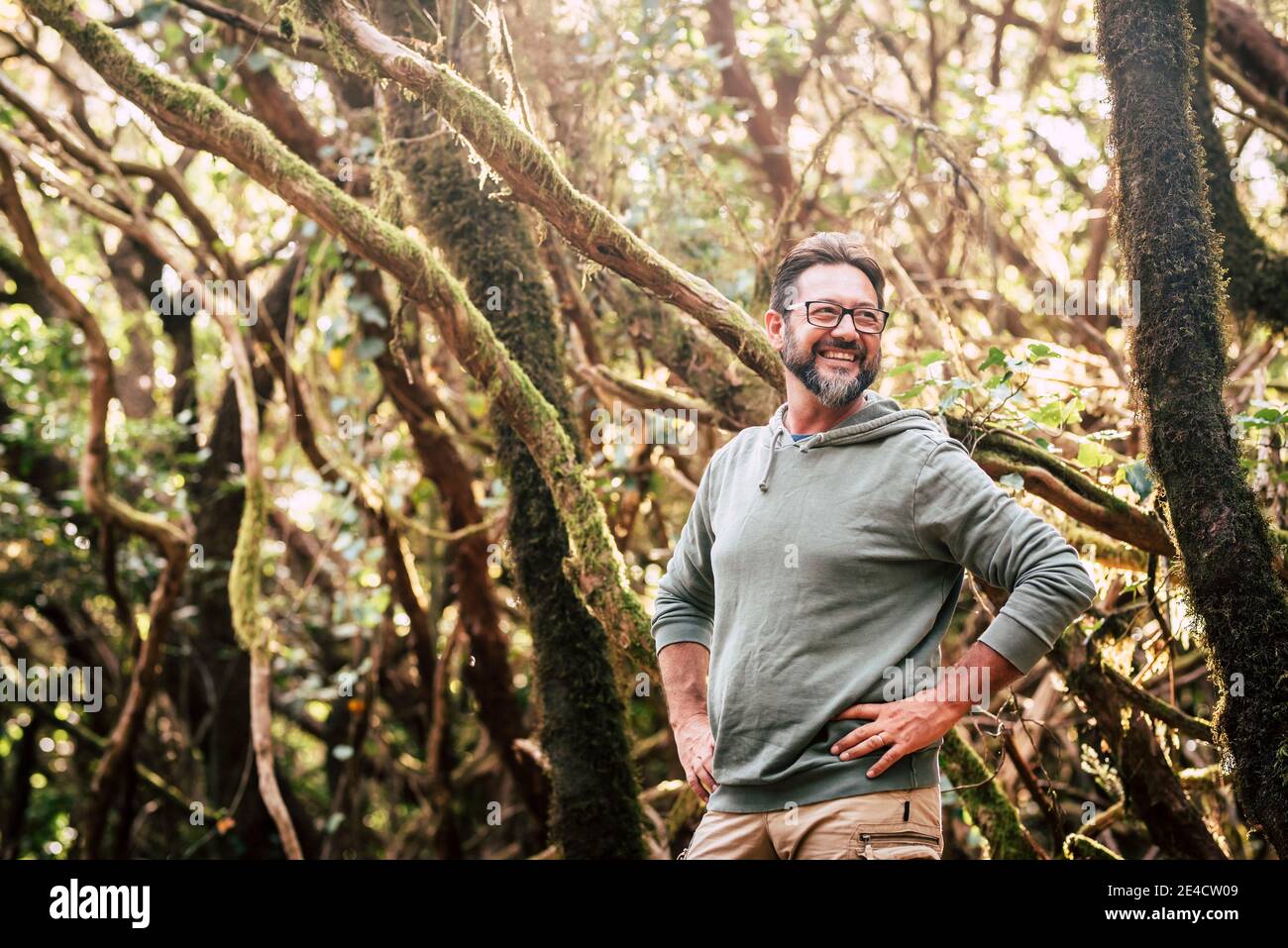 Cheerful handsome adult man portrait in outdoor park leisure activity with trees and forest wood in background - people embracing outdoors nature life and have fun adventure Stock Photo