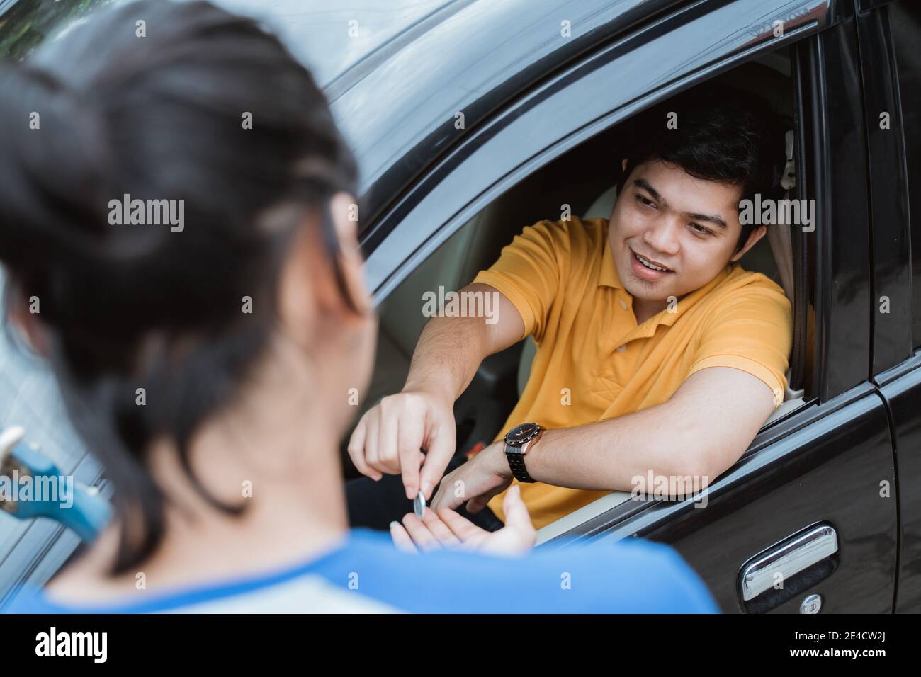 a man from the car gave coin by hand from the car window to busker on the street Stock Photo