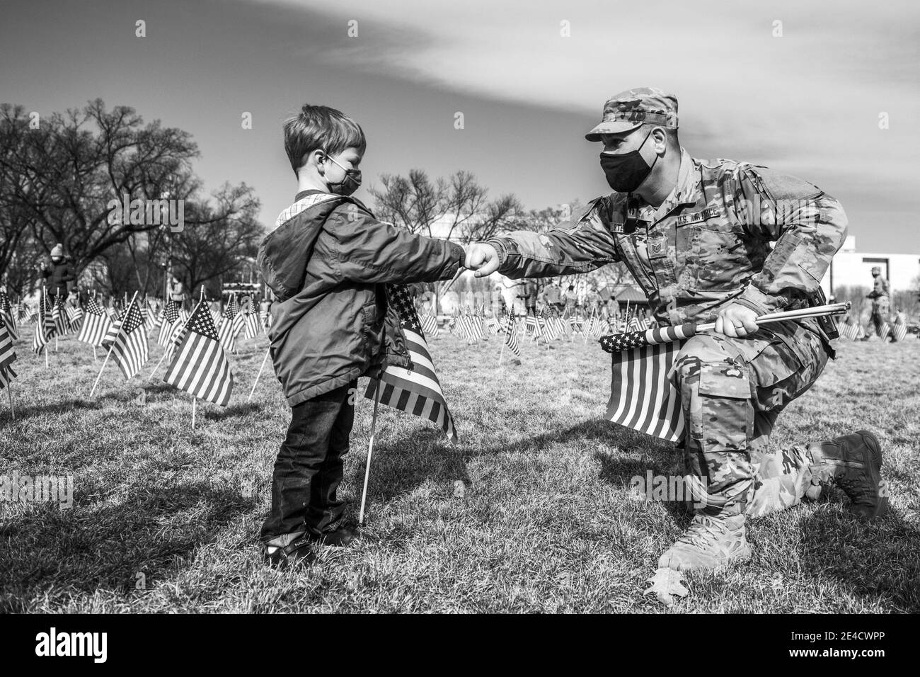 Washington, Dc, United States. 22nd Jan, 2021. WASHINGTON D.C., JANUARY 22- A boy fist bumps a member of the National Guard as they walk through'The Field of Flags' at the National Mall as it's disassembled flag by flag on January 22, 2021 in Washington, DC Nearly 200,000 flags were placed on the grass to represent Americans who died from Covid-19 and couldn't be in attendance for the ceremony. Photo: Chris Tuite/ImageSPACE Credit: Imagespace/Alamy Live News Stock Photo