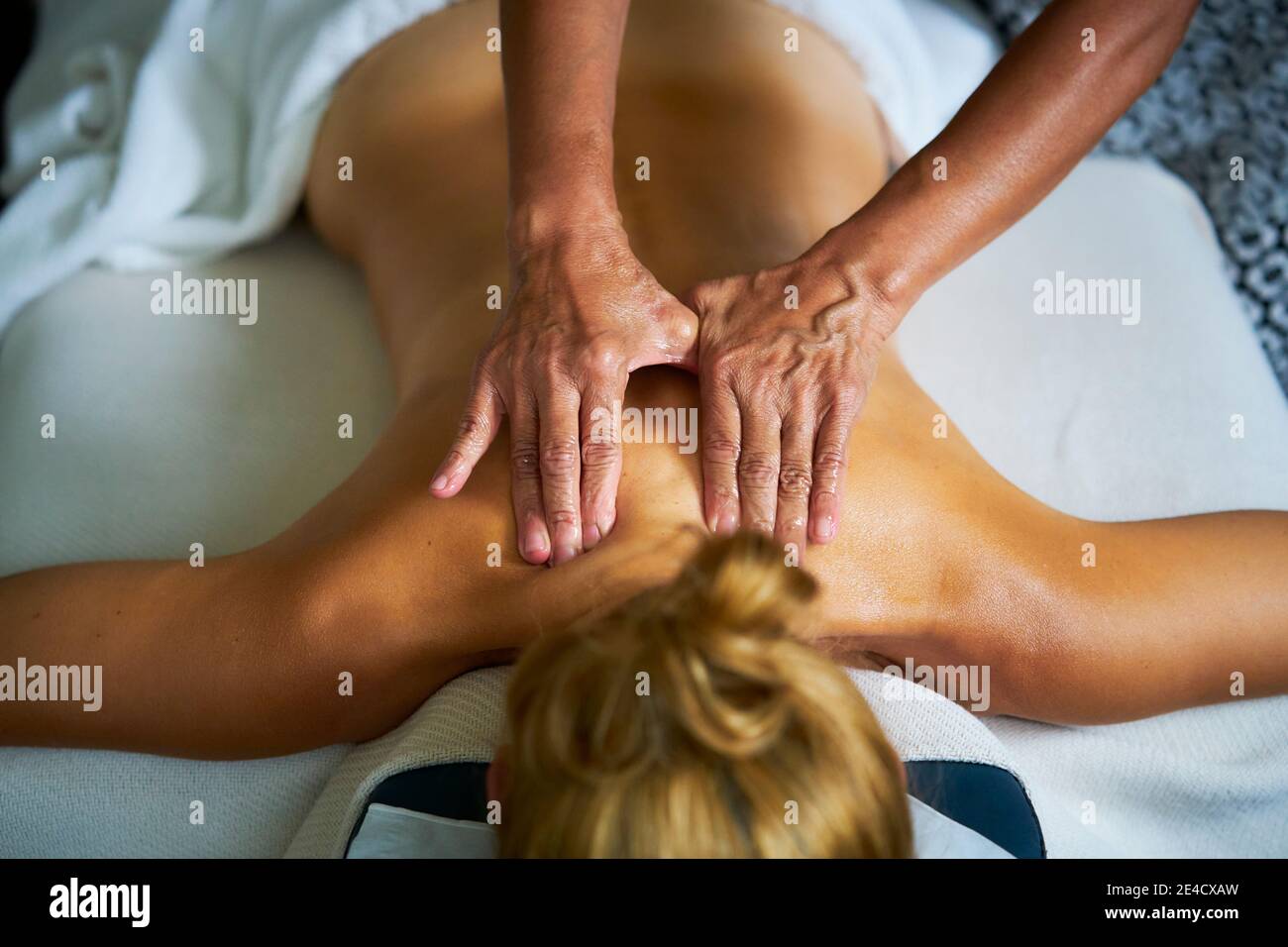 A woman receiving a full body oil massage by a professional masseuse Stock Photo