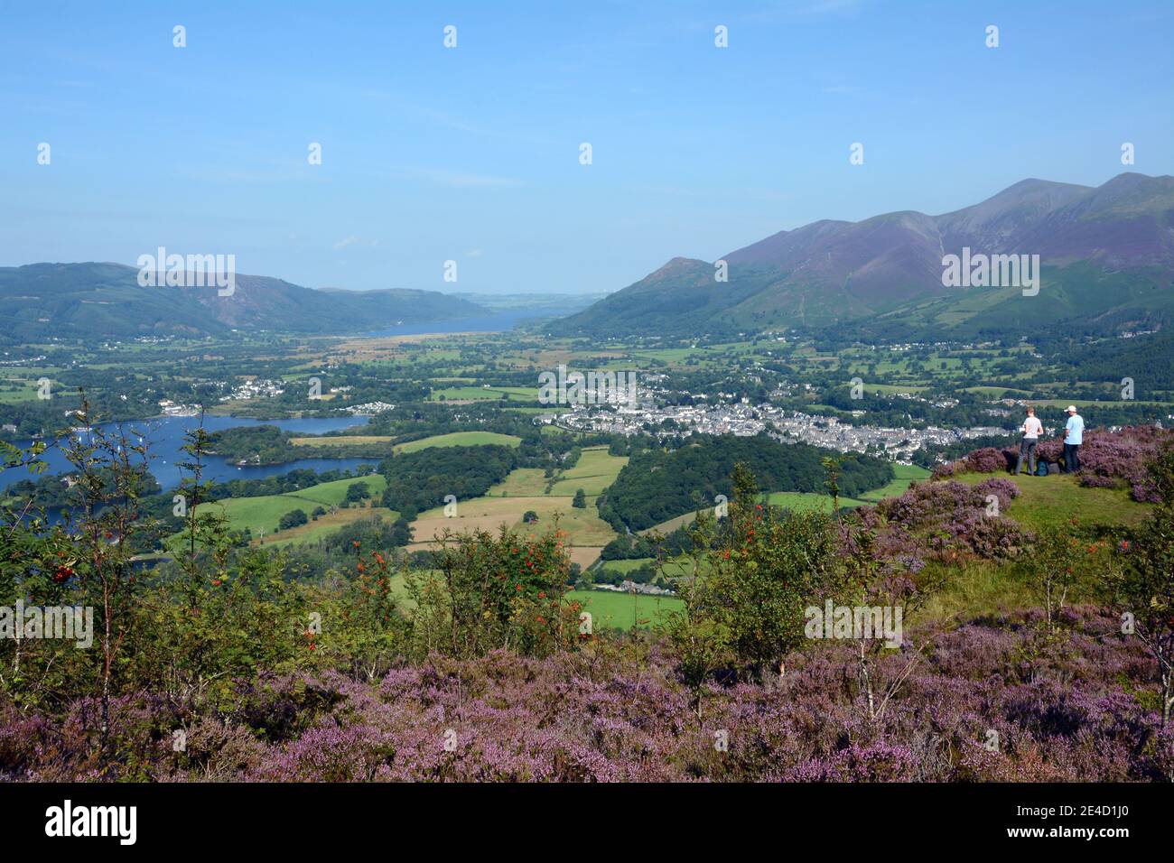 2 walkers stop to take in the stunning view looking across to Keswick in the lake district, England. Stock Photo