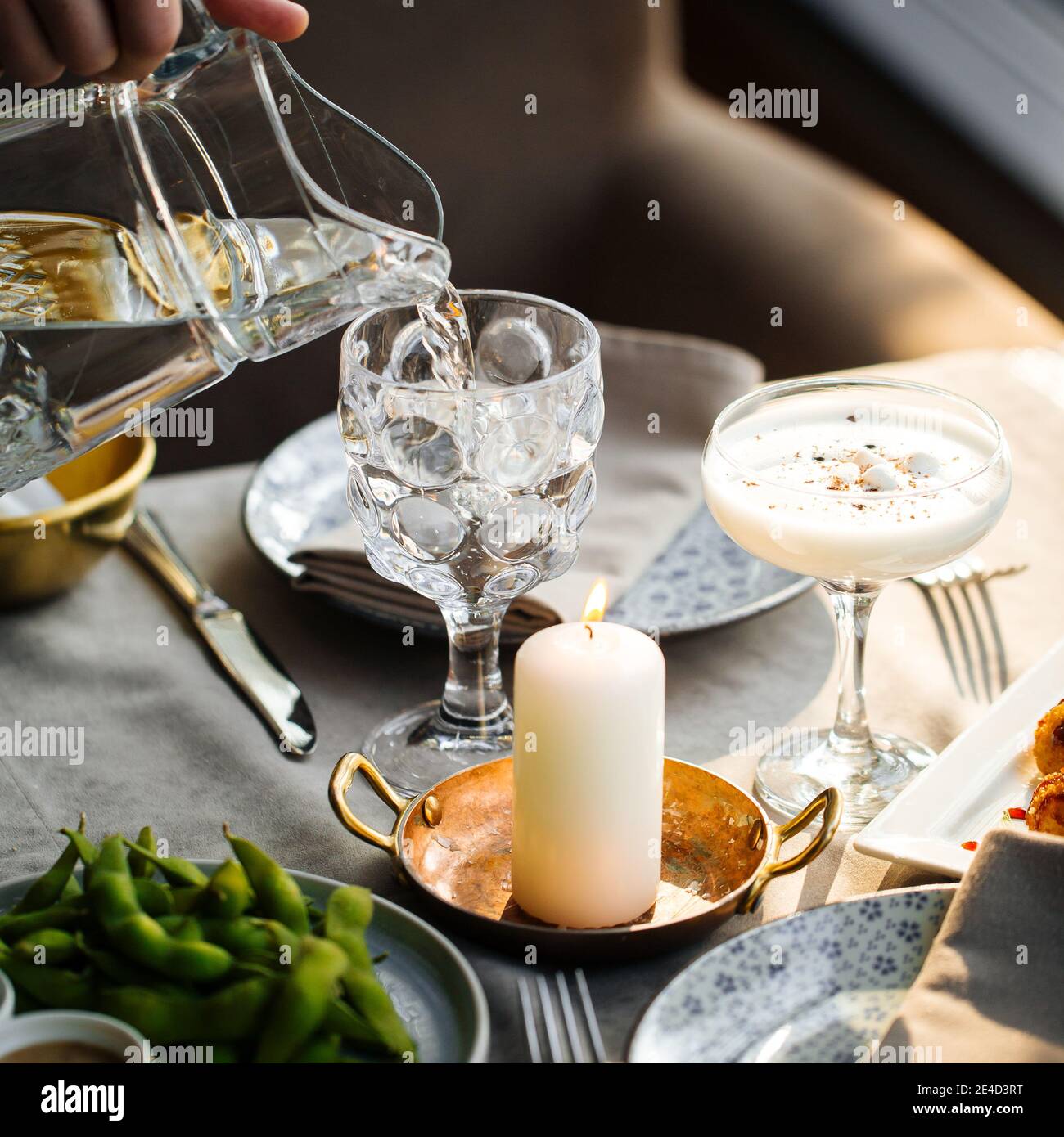 Pouring water in a glass from a jug Stock Photo