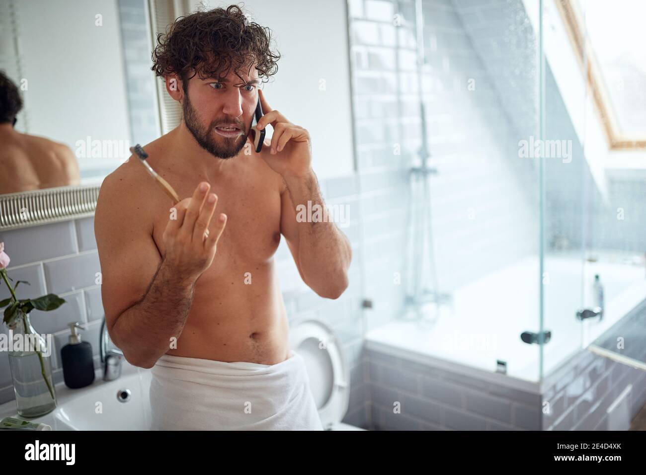 Topless man fighting while brushing teeth in the bathroom Stock Photo