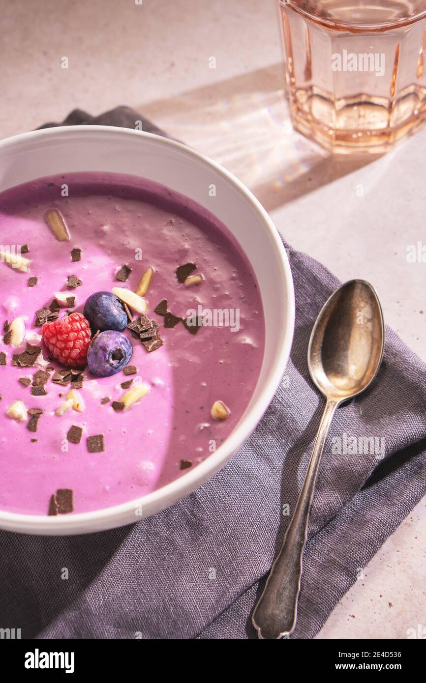 Close up of a purple berries yoghourt with some blueberries, raspberries, almond and chocolate chips on the top Stock Photo