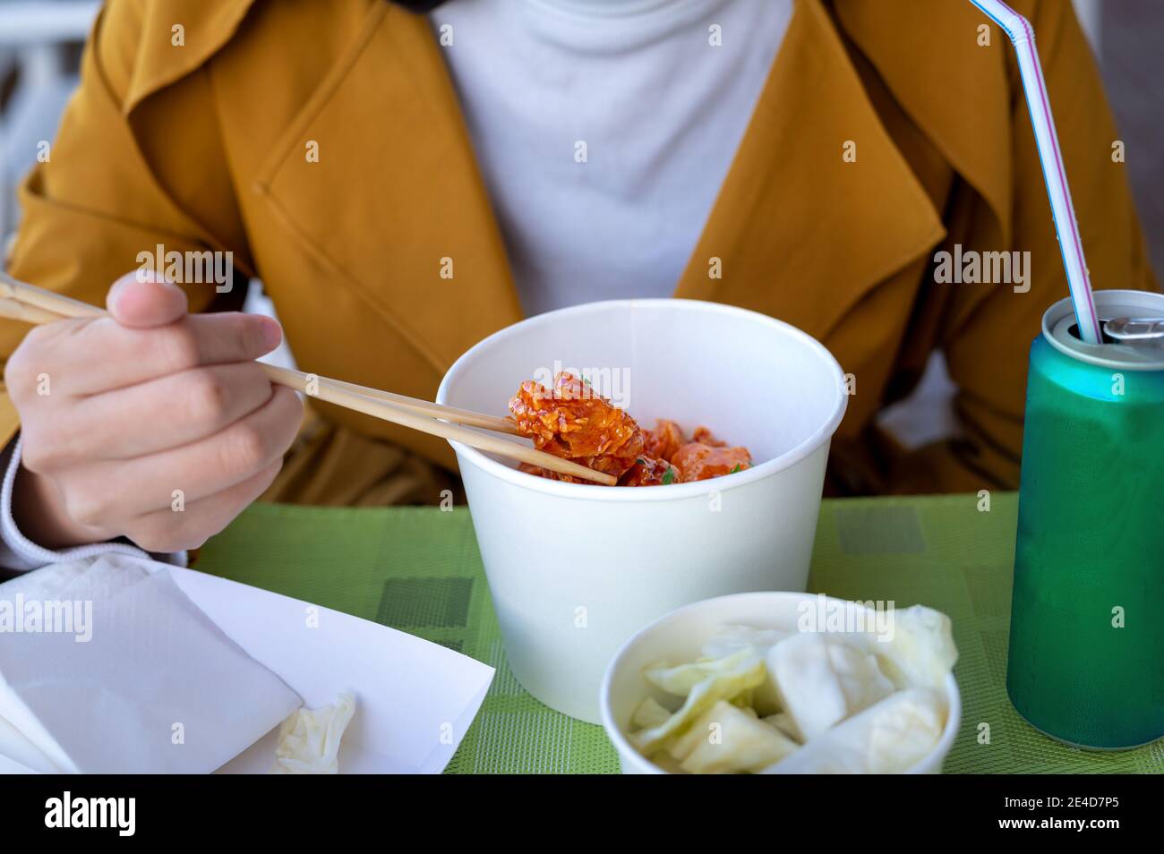 Woman having Korean deep fried chicken in a restaurant using chopsticks closeup Stock Photo