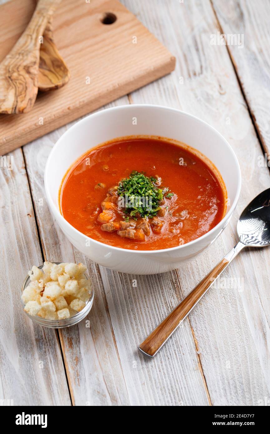 Side view on tomato soup in a bowl on wooden table Stock Photo