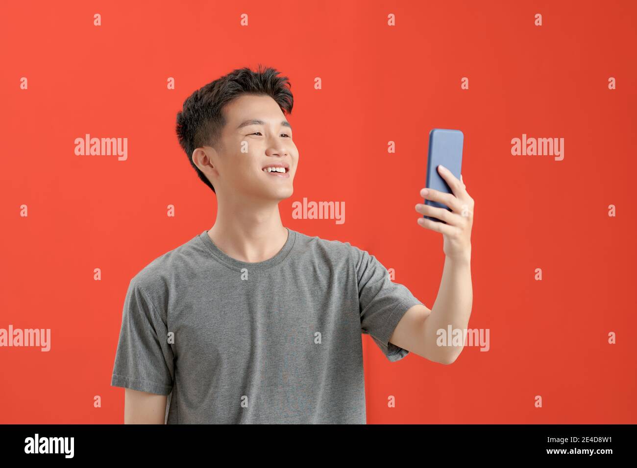 a Asian man with brown jacket making a selfie over isolated red background Stock Photo