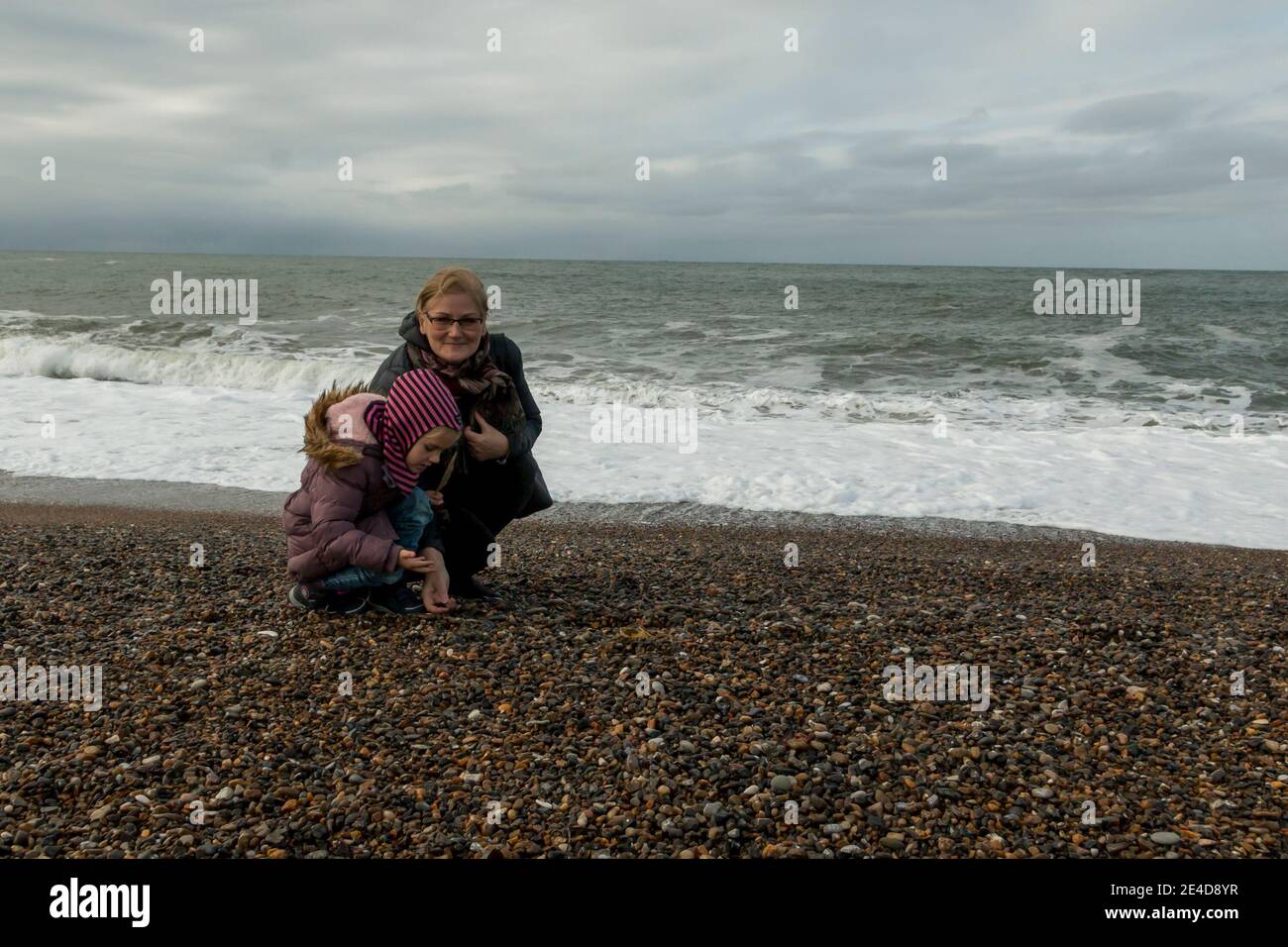 Mother and daughter collecting rocks on the beach, the west coast of Denmark, the beach at Thyboron, waves on the sea, clouds. Stock Photo