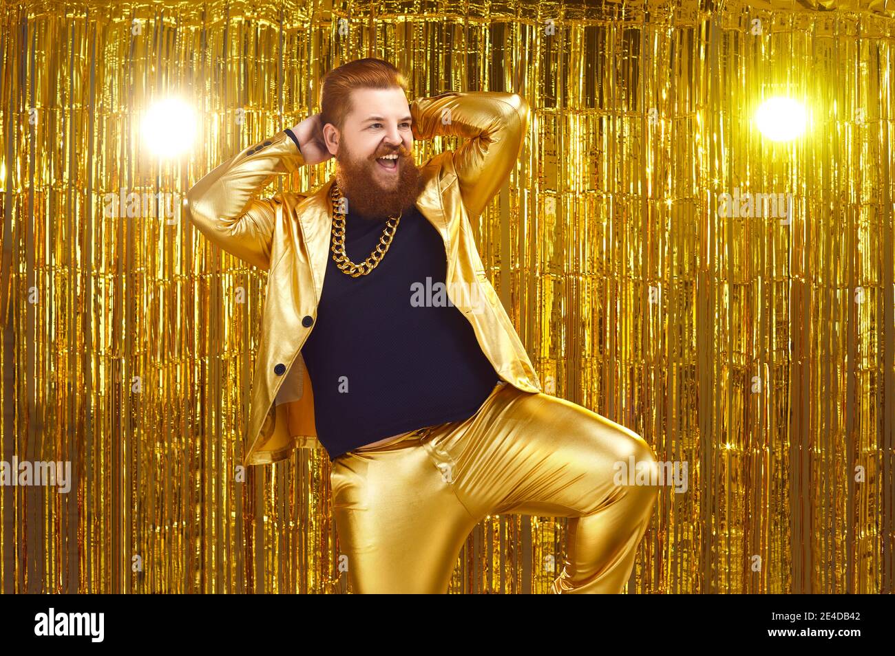 Happy confident bearded man in golden party suit dancing and having fun at disco club Stock Photo