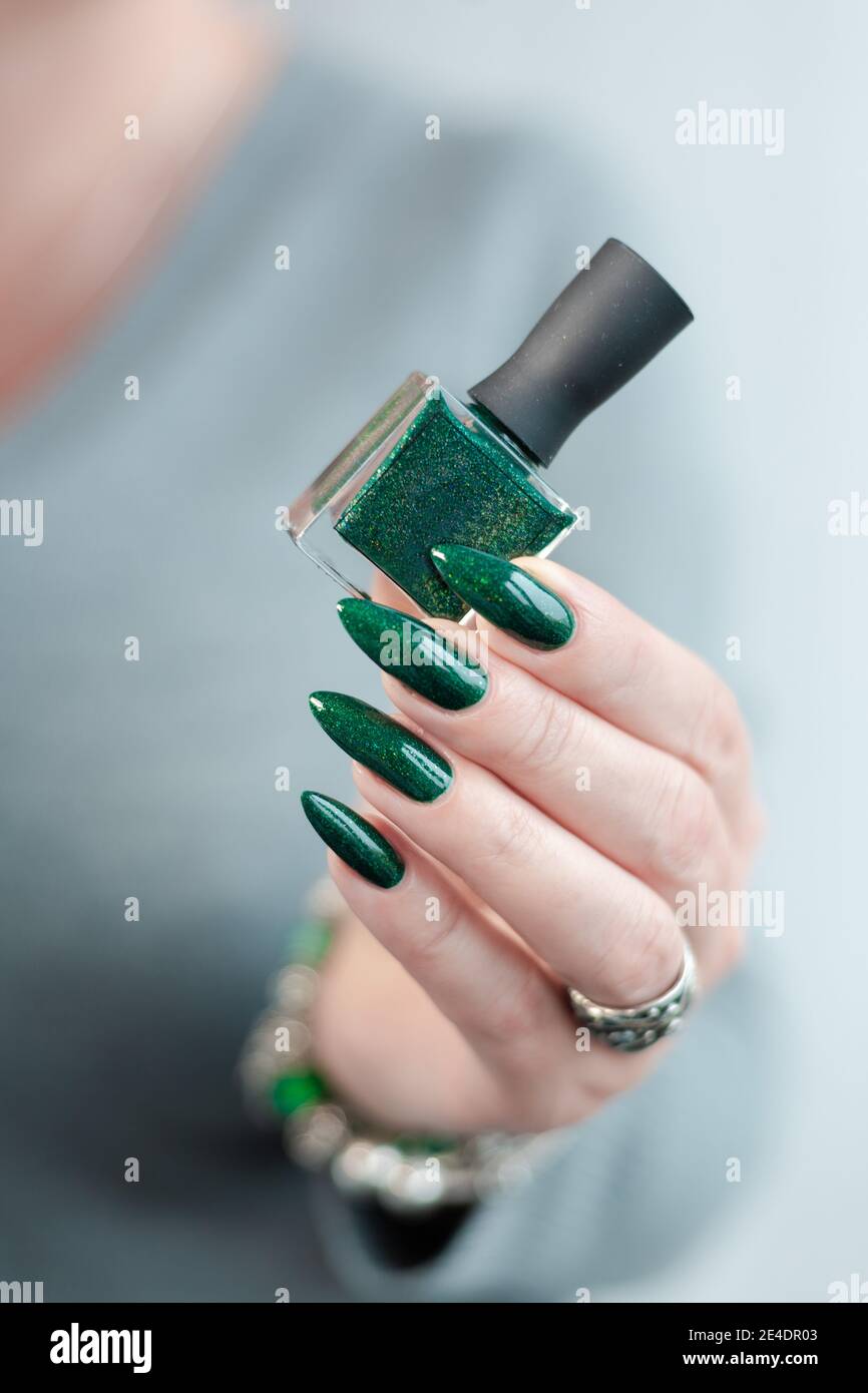 Female hand with long nails and green manicure with bottles of nail polish  Stock Photo - Alamy