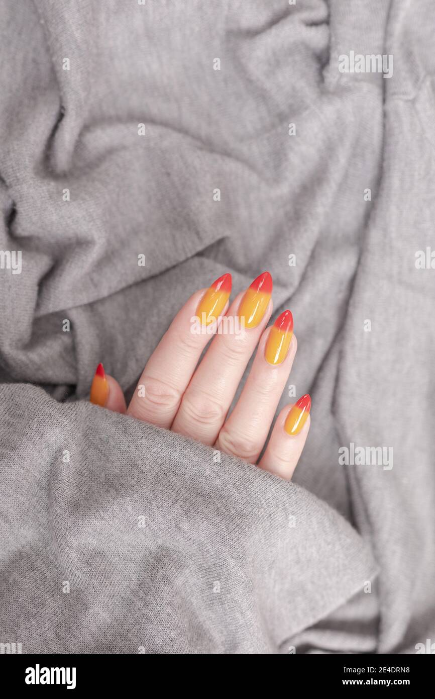 Female hands with long nails with yellow and red nail polish Stock Photo